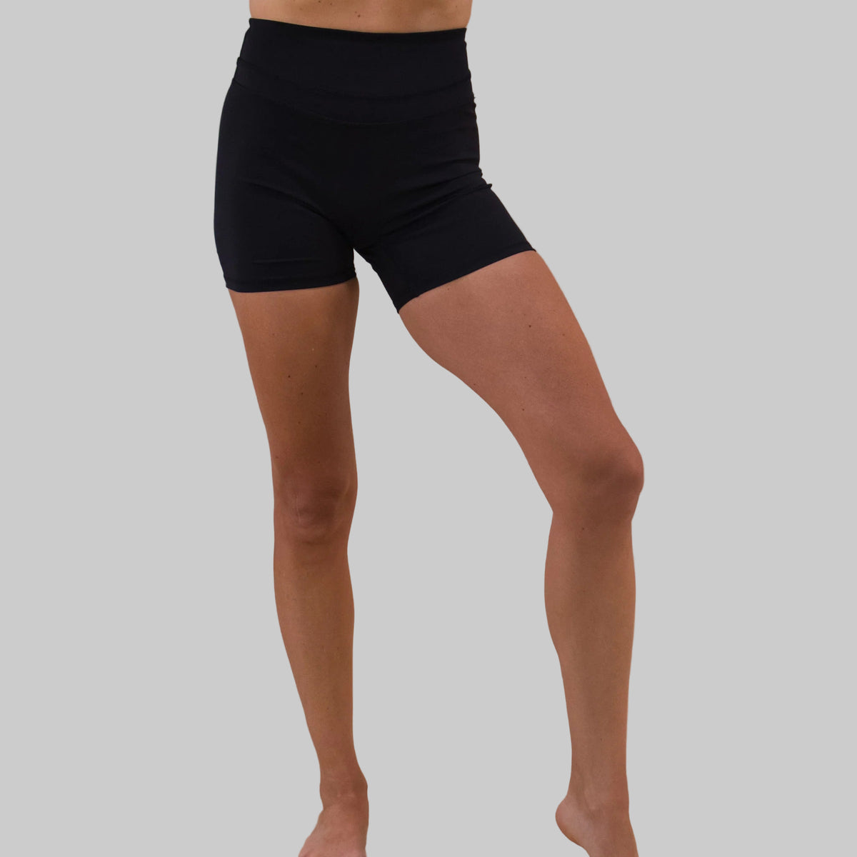 Person wearing black shorts on a beige background