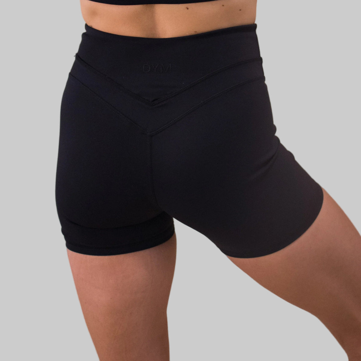 Black athletic shorts worn by a person on a beige background