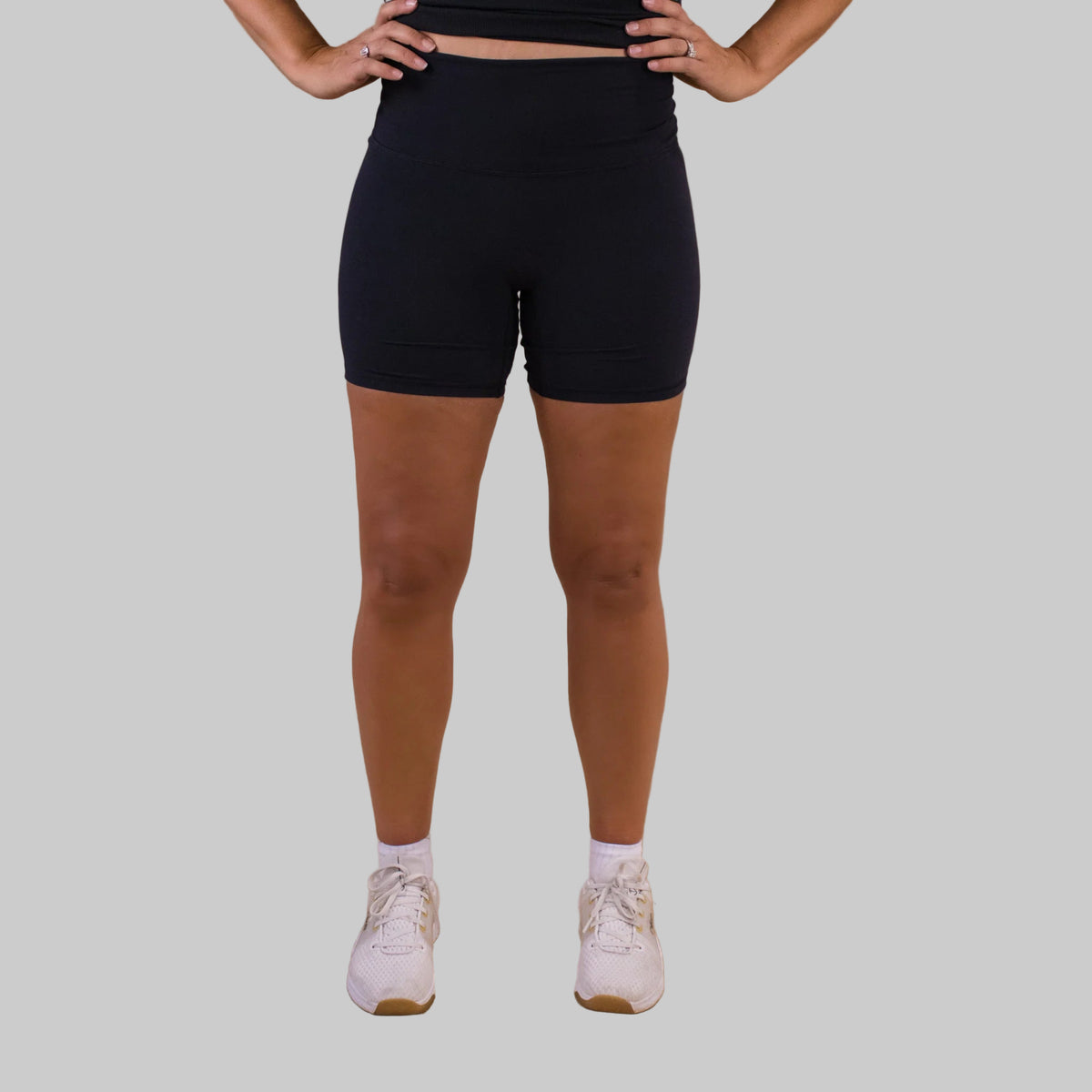 Person wearing black shorts and white sneakers on a brown background