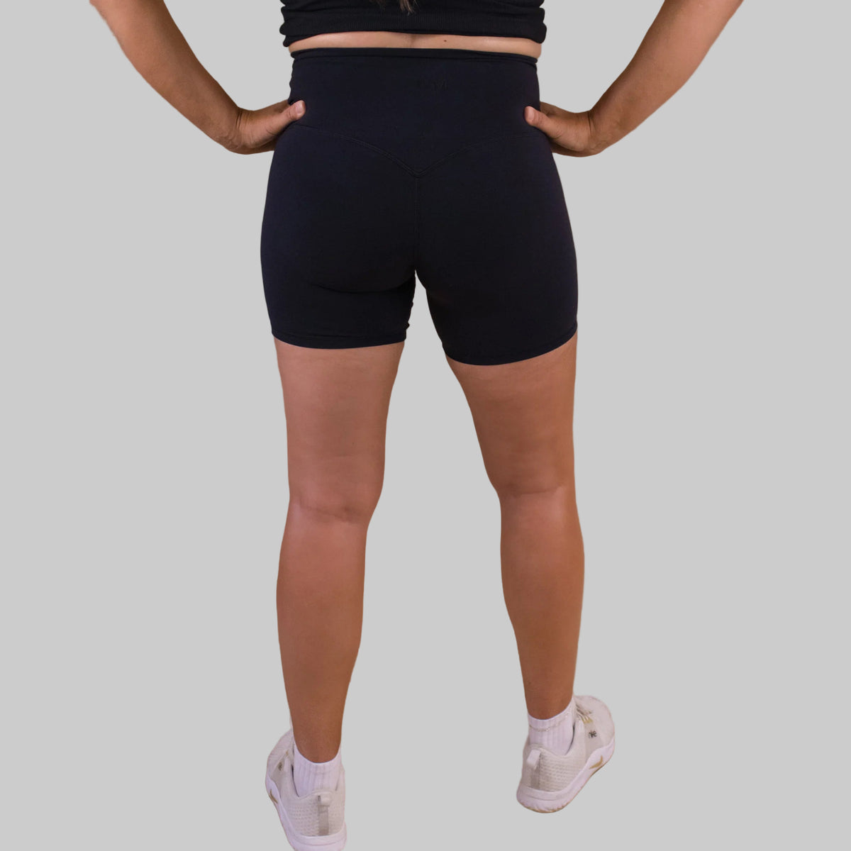 Person wearing black shorts on a brown background