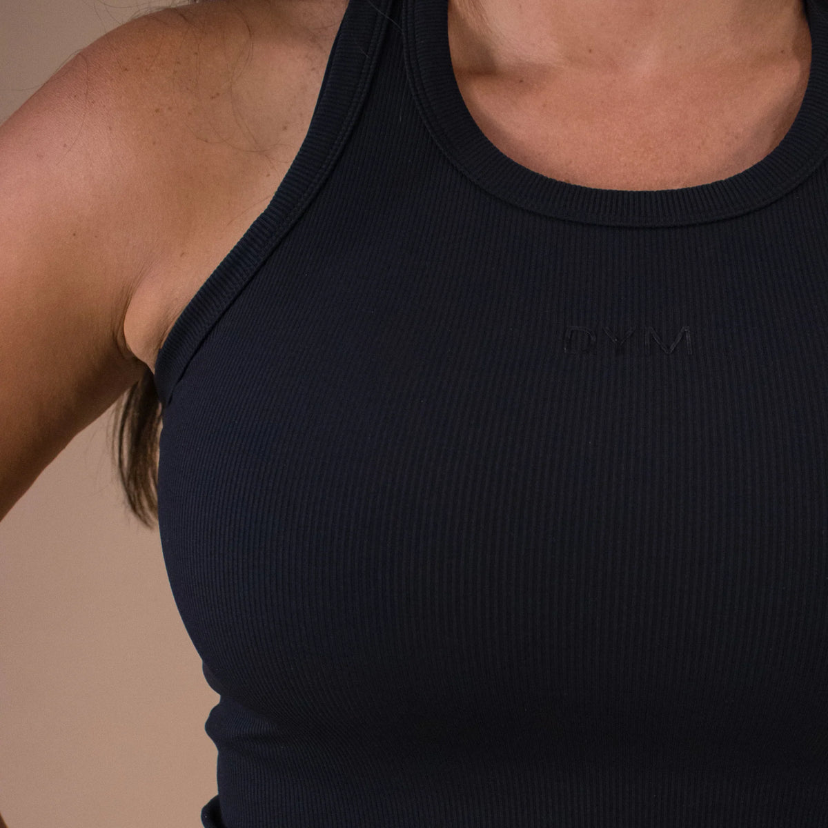 Black tank top worn by a person on a beige background
