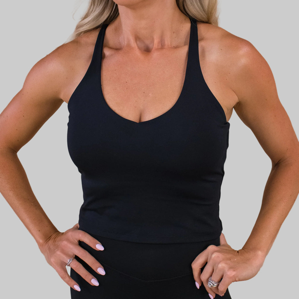 Person wearing a black tank top against a beige background