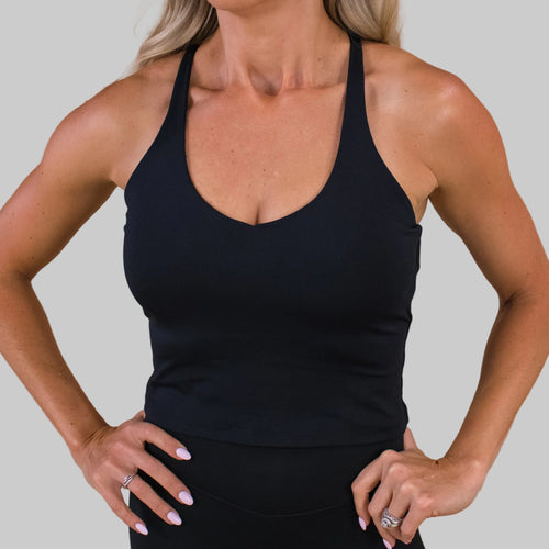 Person wearing a black tank top against a beige background