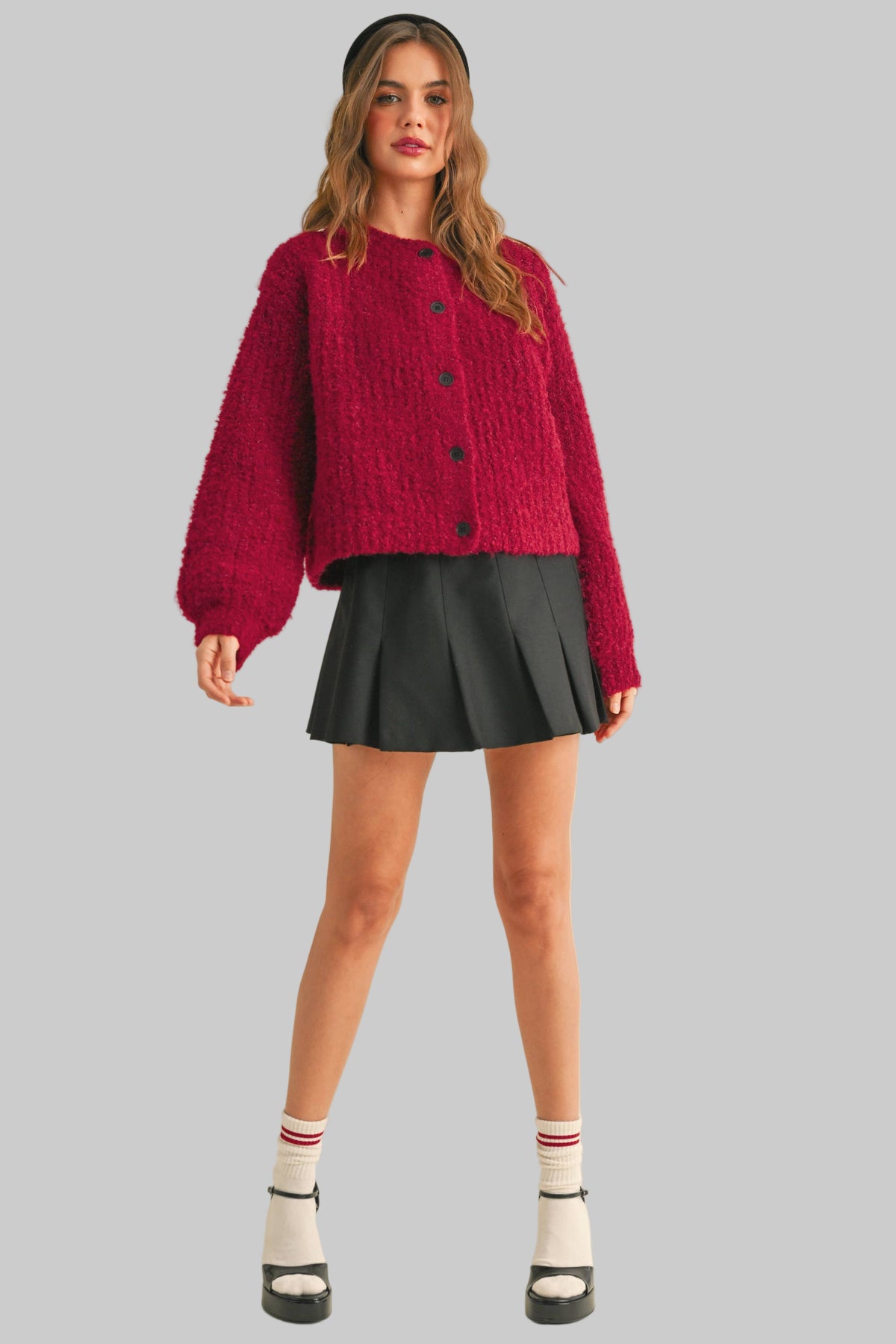Woman wearing a red sweater and black skirt on a beige background